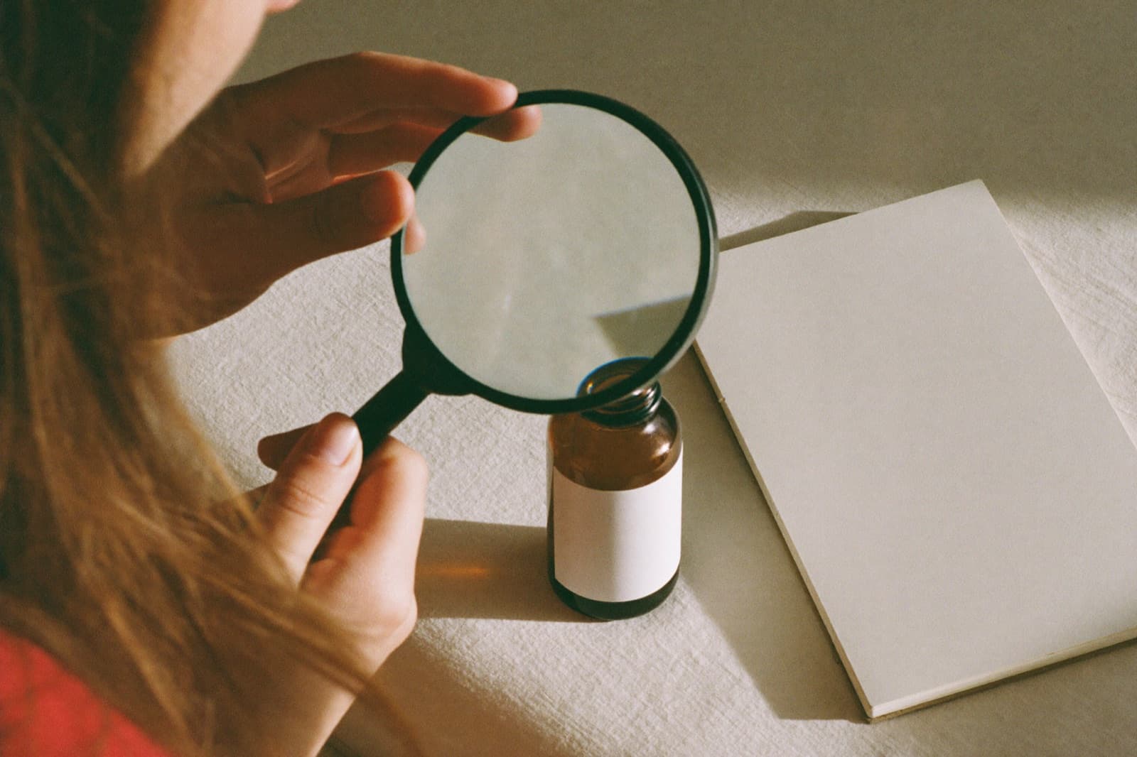 Checking a cosmetic bottle's label with a magnifying glass