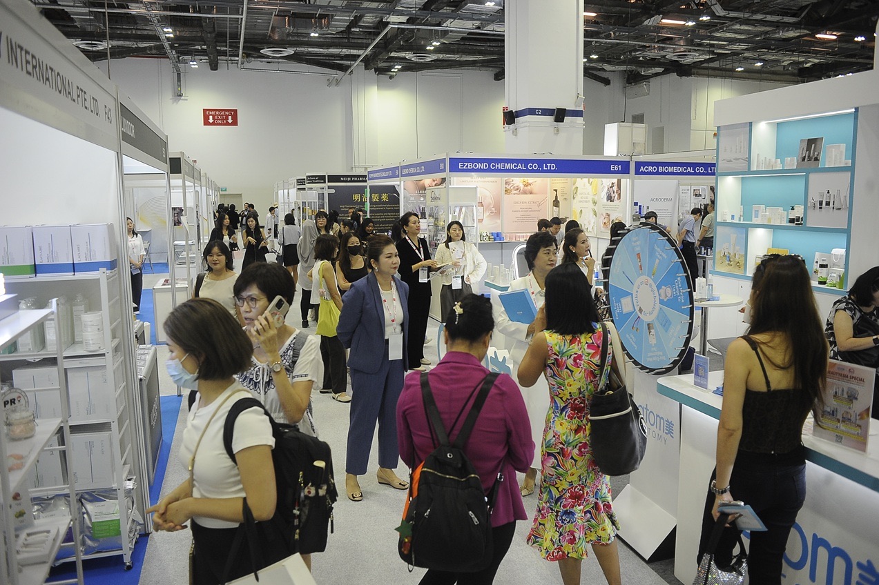 Trade visitors with badges walking a busy aisle of cosmetics and skincare exhibitor booths at BeautyAsia 2026, Marina Bay Sands Expo, Singapore
