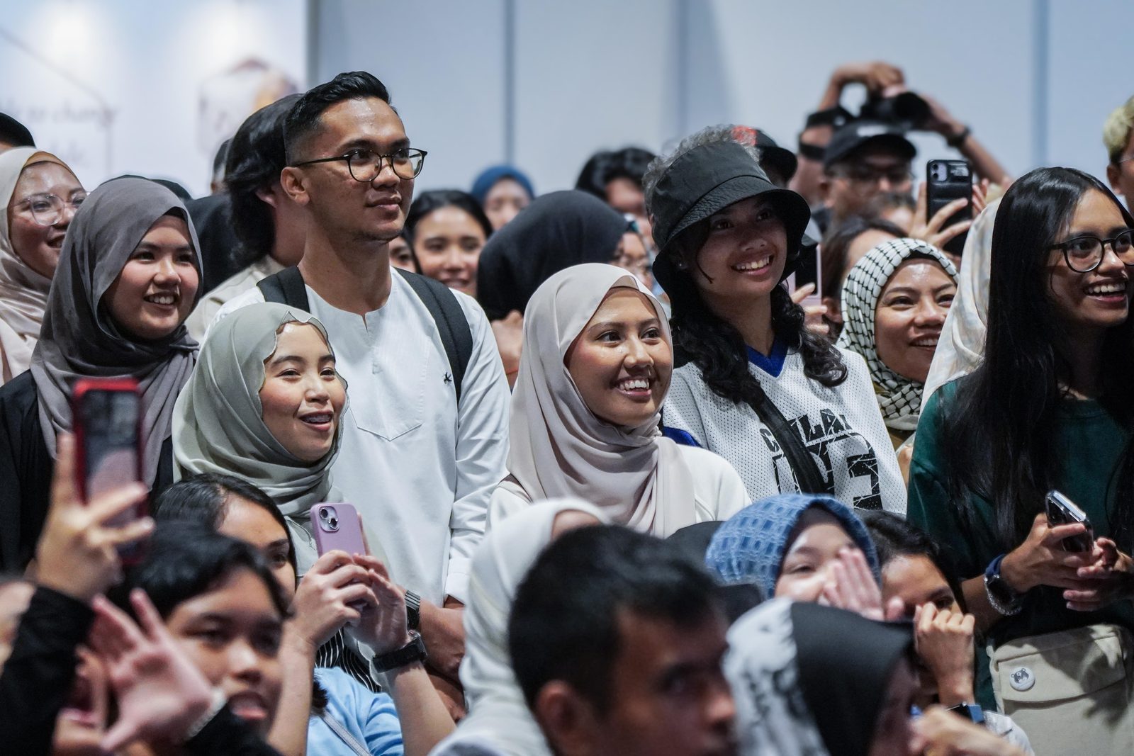 A standing crowd of young adults smiles towards a stage, some holding up phones, at a past Celebfest in Singapore