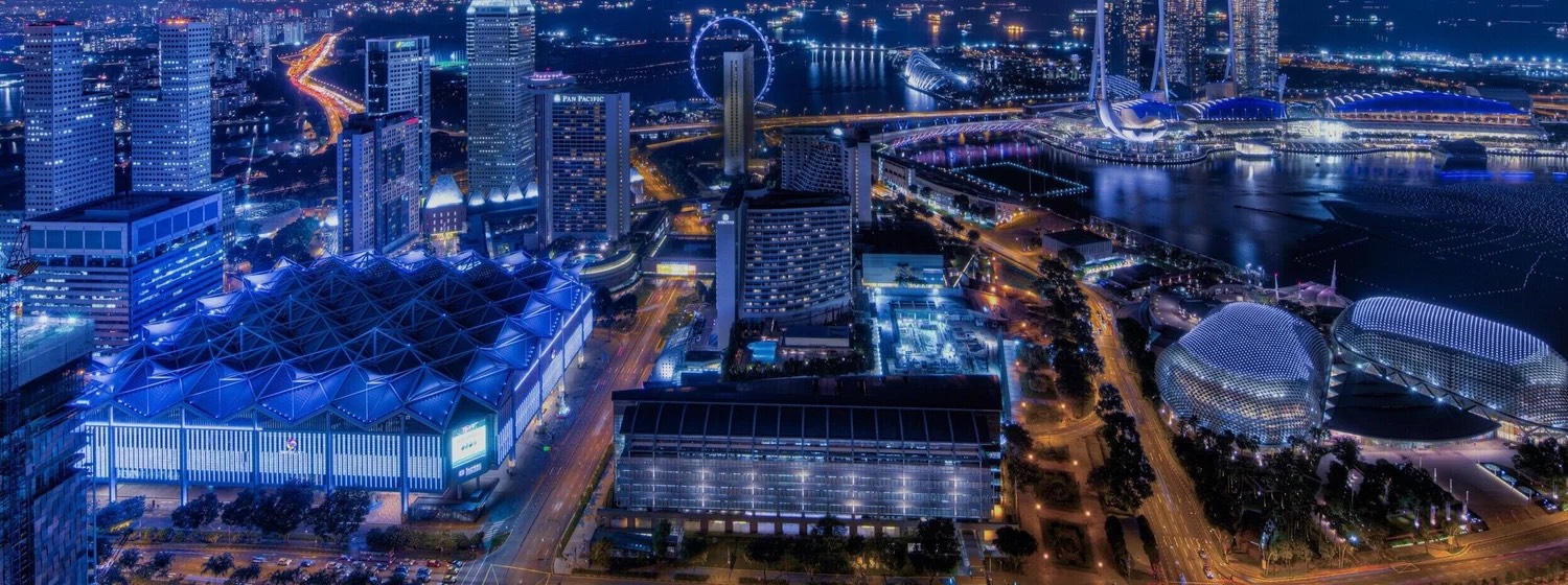 Night aerial view of Suntec Singapore Convention & Exhibition Centre with its lit pyramid roof, beside the Esplanade and Marina Bay, Singapore