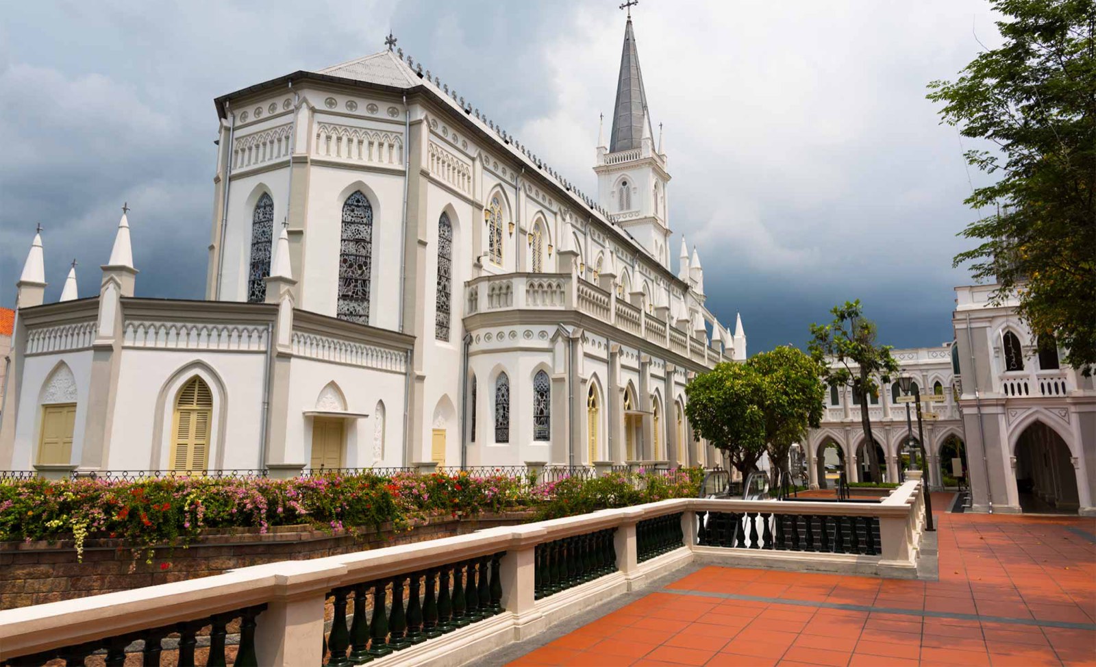 The white Gothic CHIJMES Hall and its spire beside the terracotta-tiled courtyard and arcades of CHIJMES, Victoria Street, Singapore
