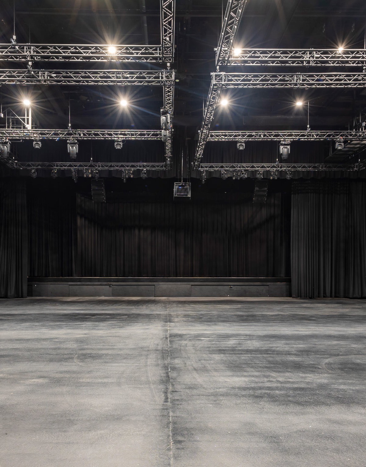 Empty flat-floor interior of the *SCAPE Ground Theatre in Singapore, with lighting trusses and black stage curtains