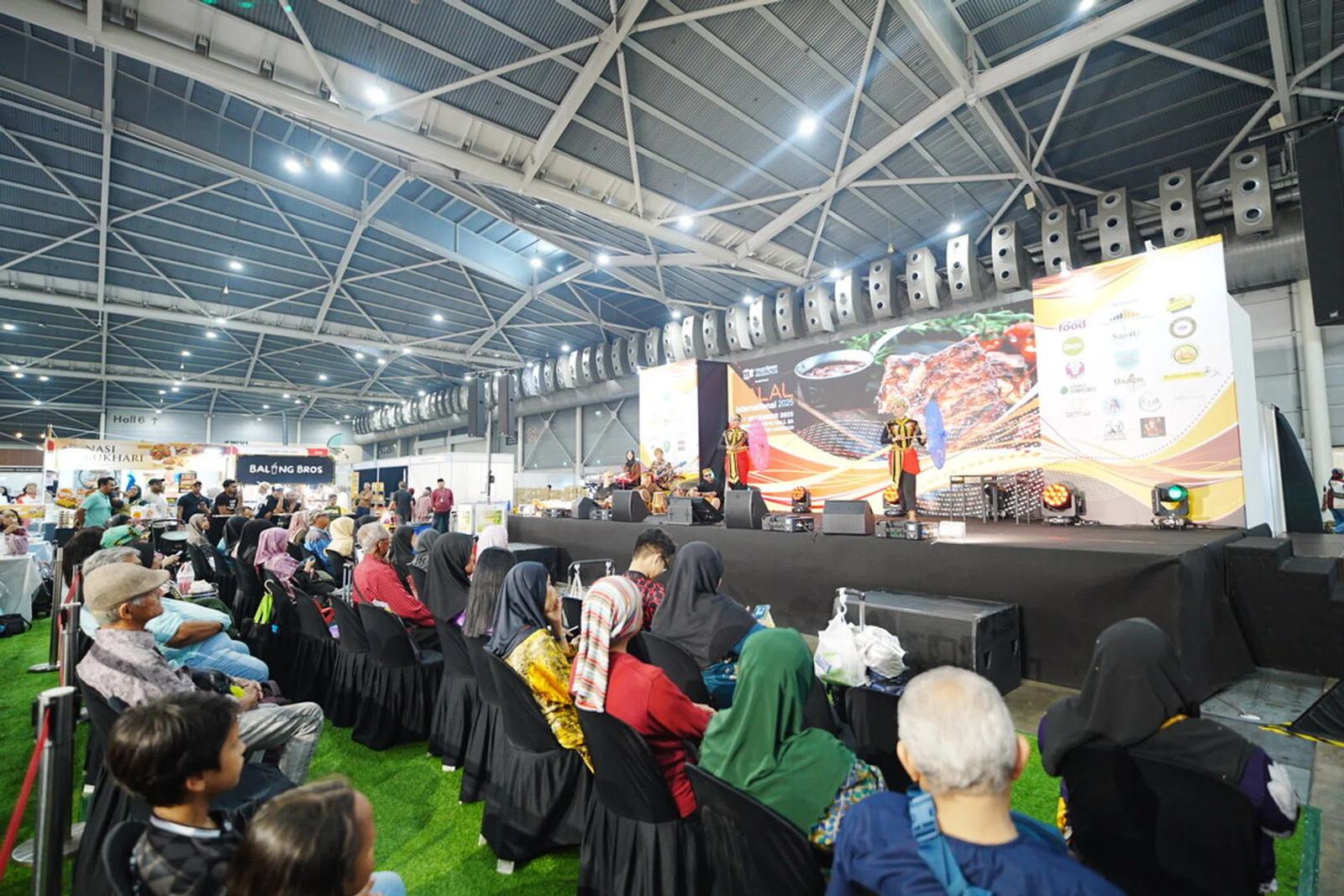 Visitors seated on artificial turf watch a traditional dance on stage at Halal International in Singapore EXPO Hall 5A