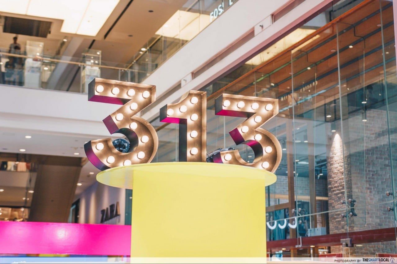 Illuminated marquee '313' sign atop a pop-up counter in the L1 atrium of 313@somerset mall, Singapore