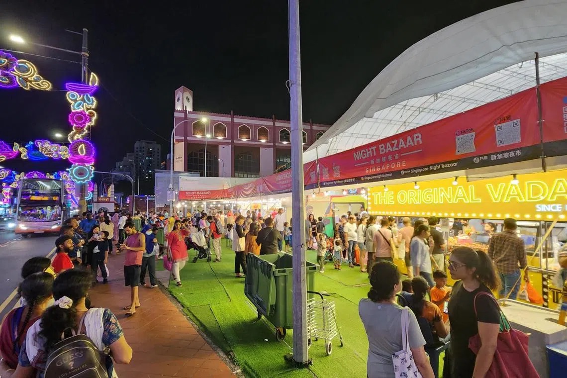 Night view of the Singapore Night Bazaar Deepavali fair tent in Little India, with Deepavali street light-up arches and crowds on the pavement