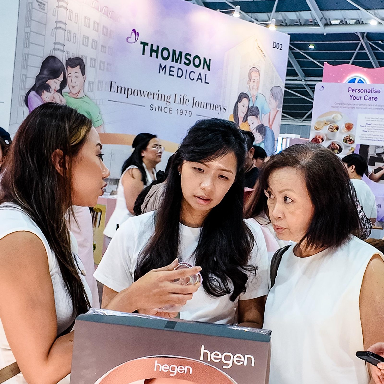 Two women listen to an exhibitor explain a breast-pump product at the Thomson Medical booth at Mummys Market Baby Fair, Singapore Expo