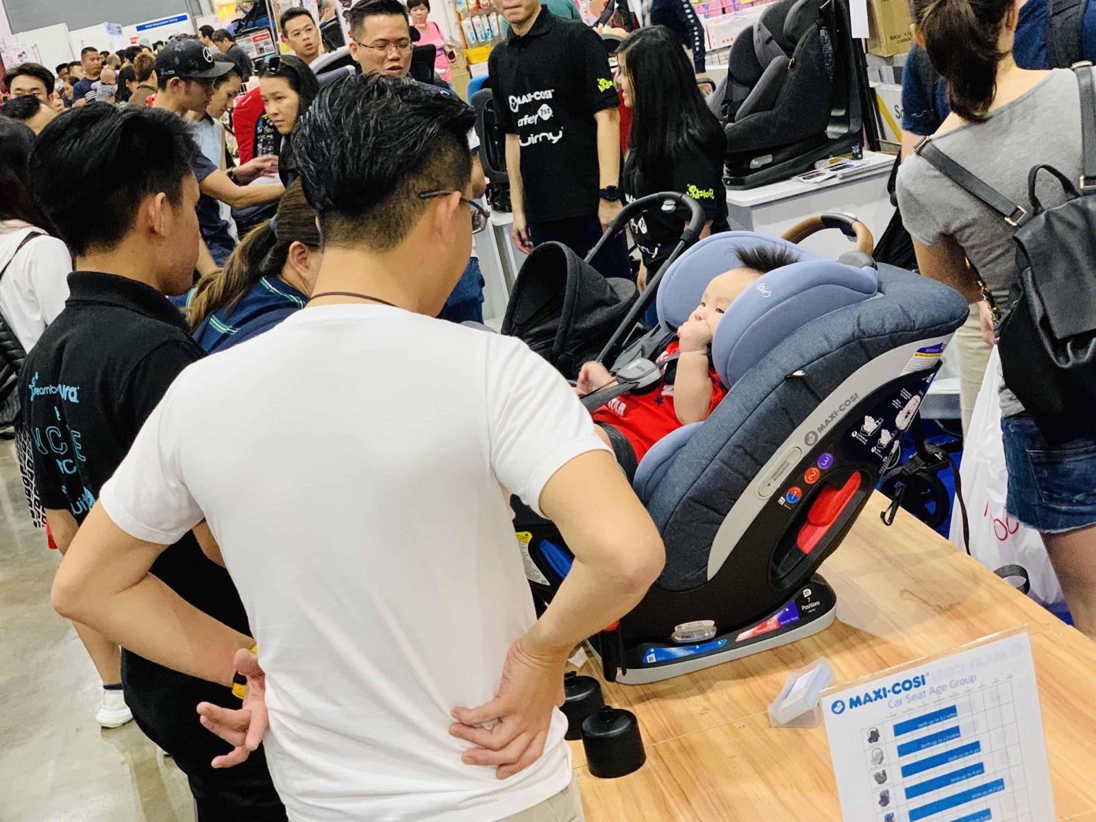 Parents watching a car-seat demonstration at a baby-gear stand at Mummys Market Baby Fair, Singapore Expo
