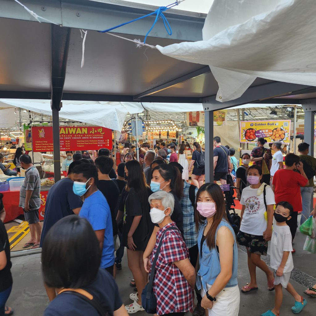 Rows of lit stalls and customers at a Singapore night bazaar