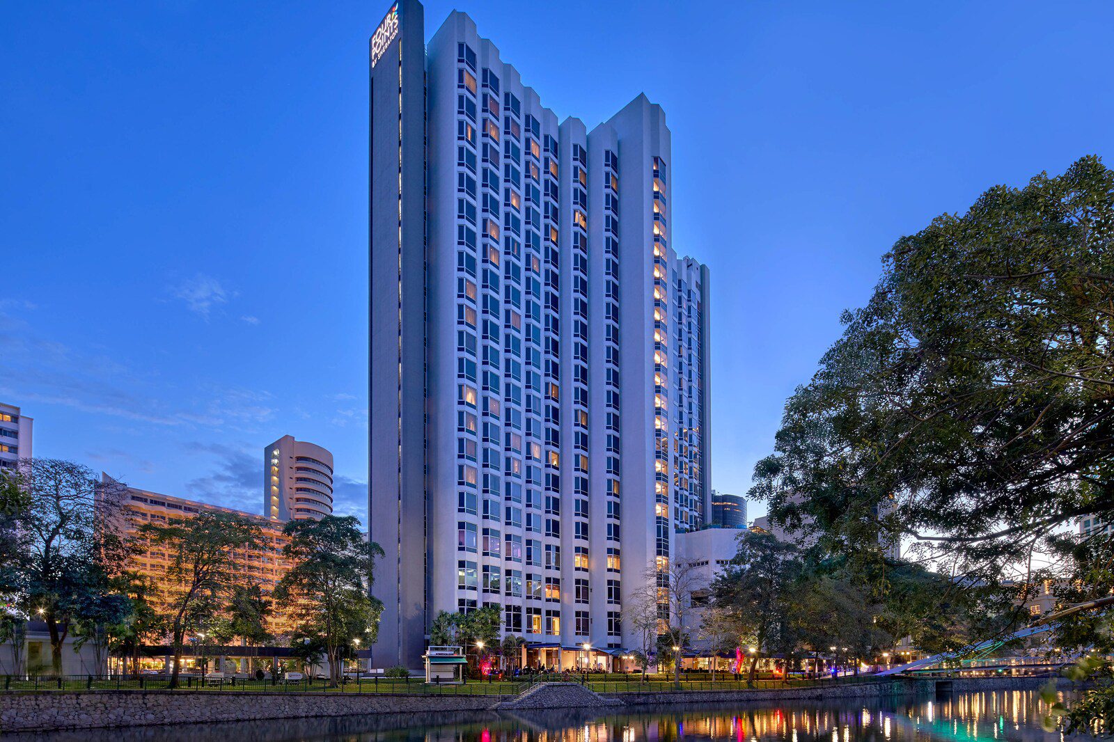 The Four Points by Sheraton Singapore, Riverview hotel at dusk, with its riverside frontage lit along the Singapore River