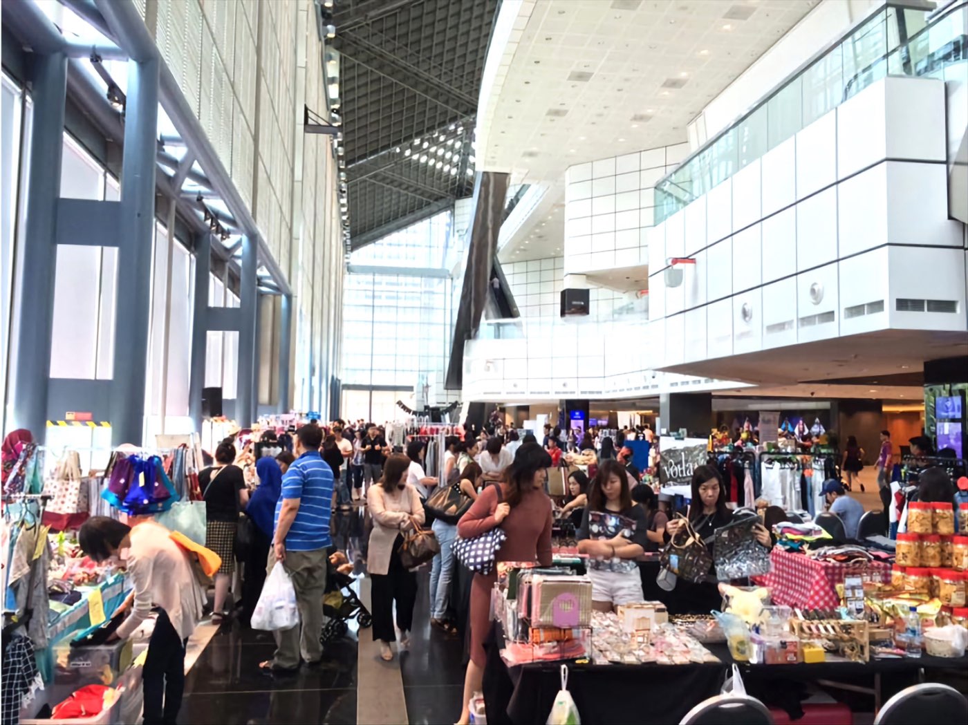 A busy T Cartel bazaar filling a mall atrium with vendor stalls, clothing racks and shoppers, Singapore