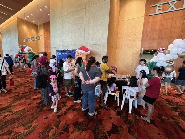 Families queue at a craft activity table beside Christmas balloon decorations outside Expo Hall A at Marina Bay Sands, Singapore