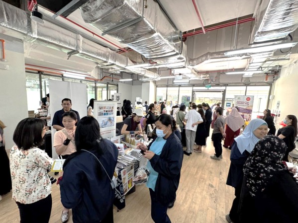 A busy bazaar unit at Woodlands Health with shoppers at product tables, Singapore
