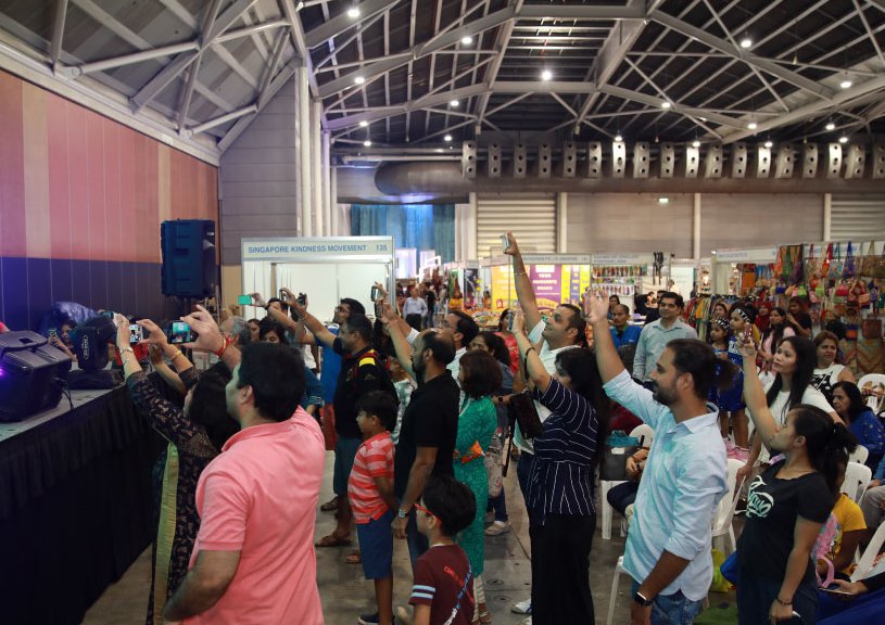 Visitors raise their phones to film a stage performance inside the exhibition hall at Zak Salaam India Expo, Singapore Expo